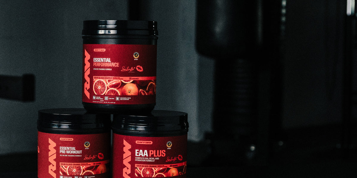 RAW x Sara Saffari Sour Blood Orange Essential Performance, Essential Pre-Workout and EAA Plus stacked in a gym