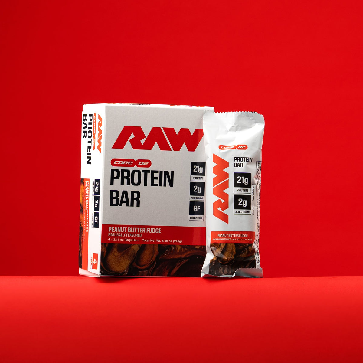 RAW Core Peanut Butter Fudge Protein Bar 4-pack box with a single bar beside it, on a red background.
